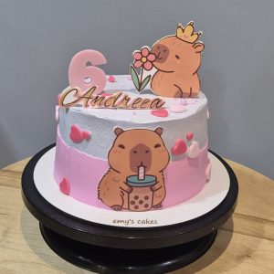 Tort copii acoperit în cremă de brânză, cu poze capybara, inimioare și cifra 6 roz