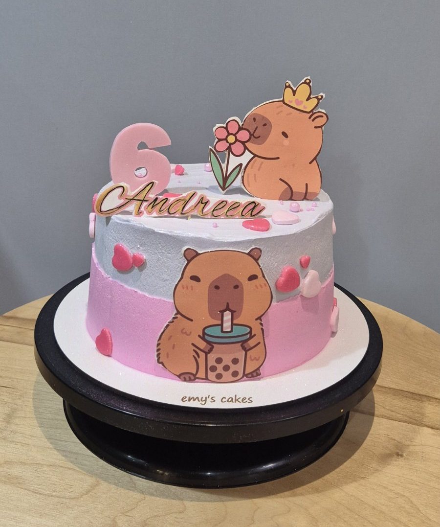 Tort copii acoperit în cremă de brânză, cu poze capybara, inimioare și cifra 6 roz