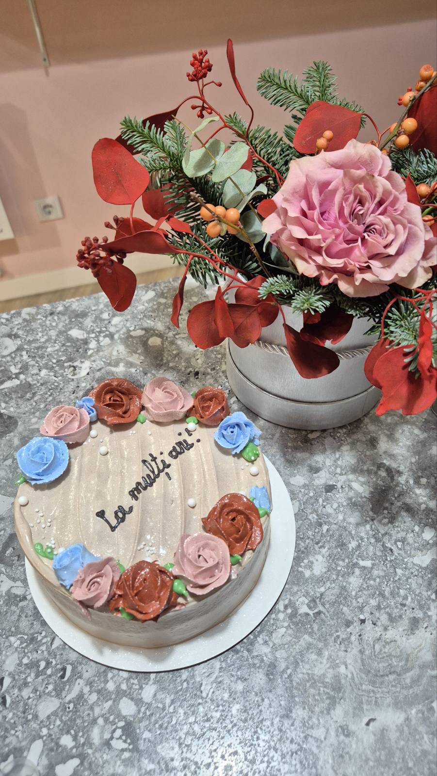 Tort crem „La mulți ani” cu trandafiri din cremă în nuanțe de roz, roșu și albastru