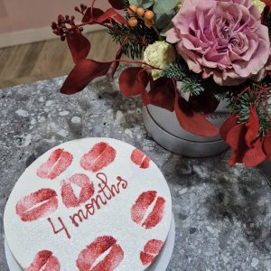Tort alb cu sclipici și amprentă de buze roșii, mesaj „4 months”