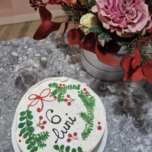 Tort alb „6 luni” cu decor de crenguțe verzi și bobițe roșii, inspirat de iarnă