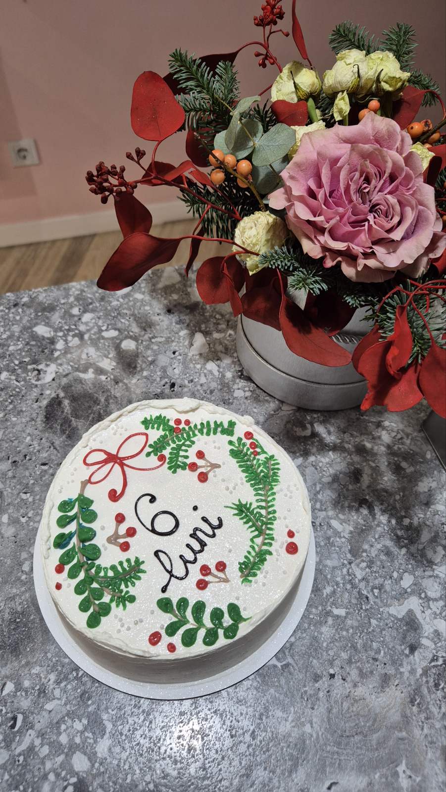 Tort alb „6 luni” cu decor de crenguțe verzi și bobițe roșii, inspirat de iarnă