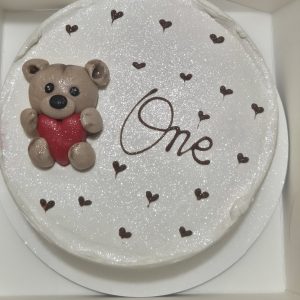 Tort bento alb sidefat cu ursuleț și inscripția „One”, perfect pentru prima aniversare.