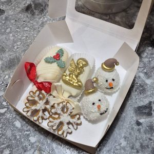 Set de Crăciun cu deserturi în ciocolată albă, îngeraș auriu, oameni de zăpadă și fulgi de nea, ambalate în cutie cadou, realizat de Emys Cakes.