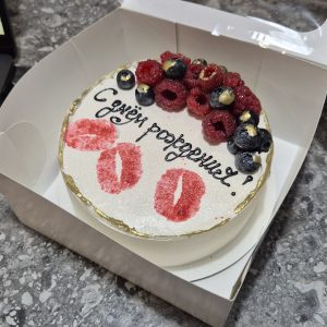 Bento cake alb cu sclipici, decorat cu zmeură și afine proaspete, urme de ruj roșu și inscripție „La mulți ani” în rusă, în cutie de cadou, realizat de Emys Cakes.