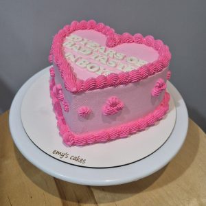 Tort în formă de inimă, acoperit în cremă roz, cu margini și decor din cremă roz intens, realizat artizanal de Emys Cakes.