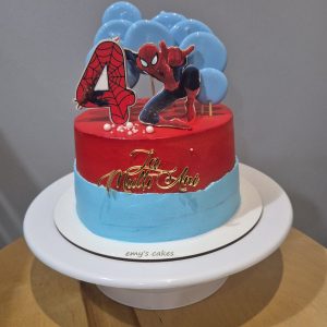 Tort pentru copii decorat în roșu și albastru, cu personaj de supererou, baloane albastre, cifră tematică și topper „La Mulți Ani”, realizat de Emys Cakes.