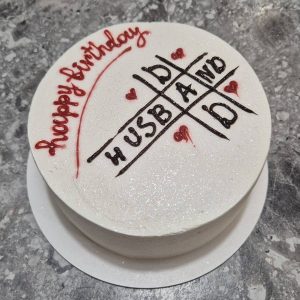 Bento cake alb sidefat cu mesaj „Happy birthday husband”, decorat cu inimioare roșii și design tip „X și 0”, realizat de Emys Cakes.