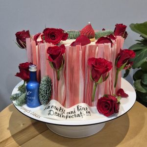Tort elegant acoperit în cremă de brânză, decorat cu foi de orez roșii verticale, trandafiri roșii naturali și crenguțe de brad, realizat de Emys Cakes.