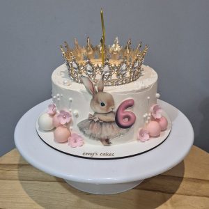 Tort aniversar pentru copii 6 ani cu iepuraș drăguț, coroană aurie, cremă de brânză, floricele roz, perle și lumânare, Emys Cakes 1.5 kg.