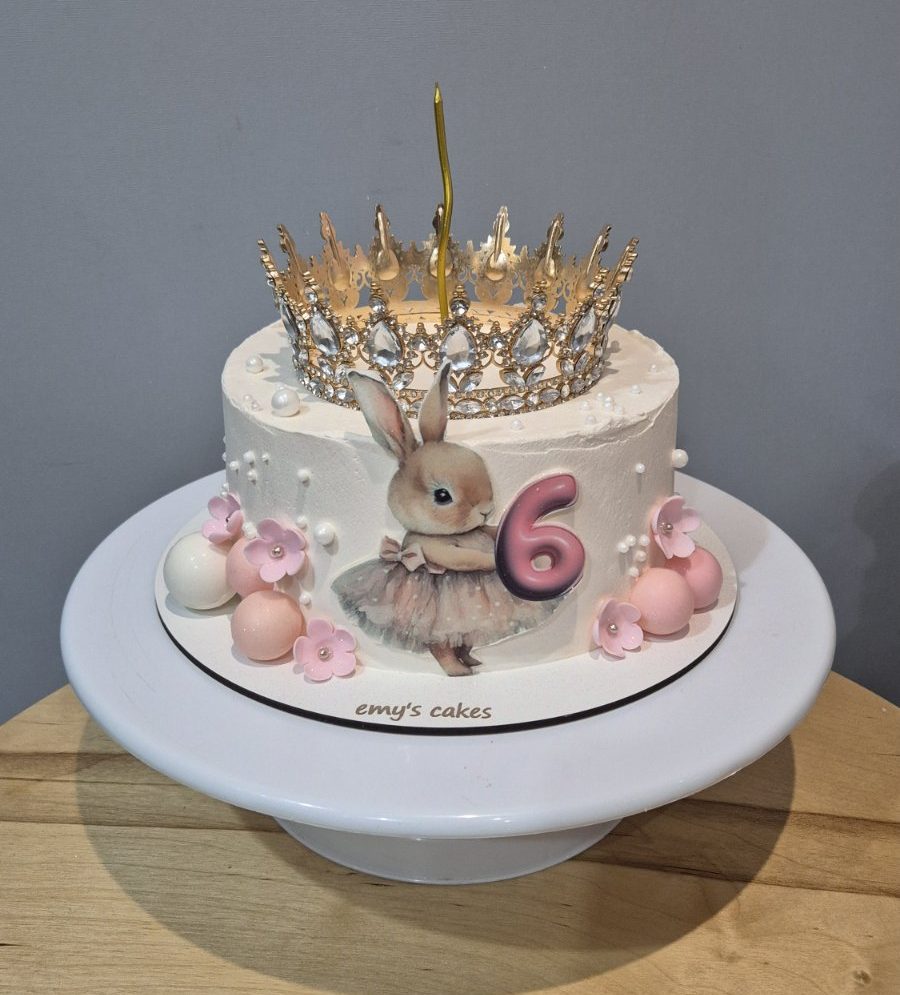 Tort aniversar pentru copii 6 ani cu iepuraș drăguț, coroană aurie, cremă de brânză, floricele roz, perle și lumânare, Emys Cakes 1.5 kg.