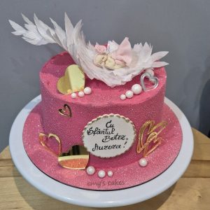 Tort de botez roz cu bebeluș adormit pe aripi albe, inimi aurii și perle
