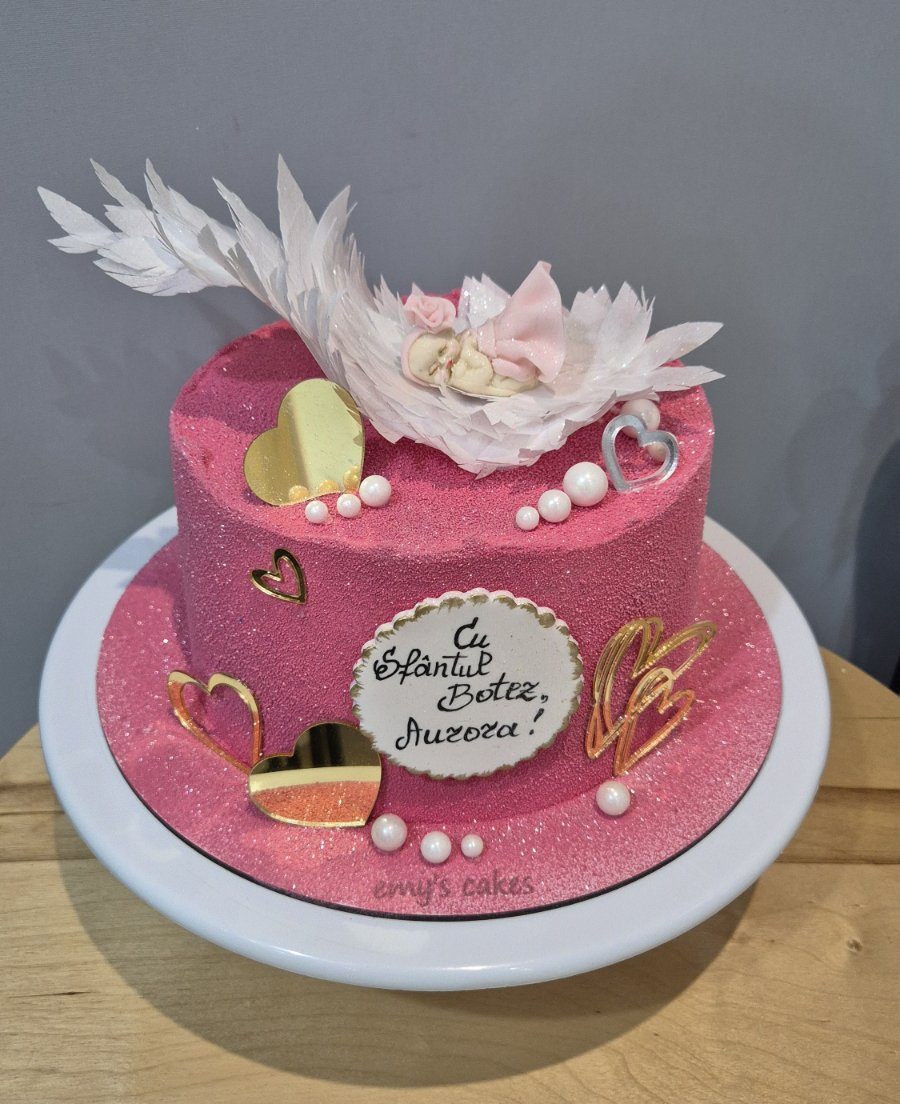 Tort de botez roz cu bebeluș adormit pe aripi albe, inimi aurii și perle