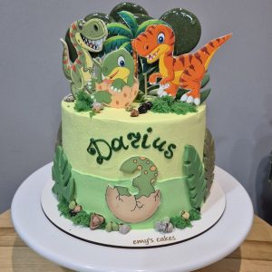 Tort dinozauri colorate pentru Darius 3 ani cu printuri, frunze verzi, ou de dino, acadele, cremă brânză verde-galben Emys Cakes 2 kg