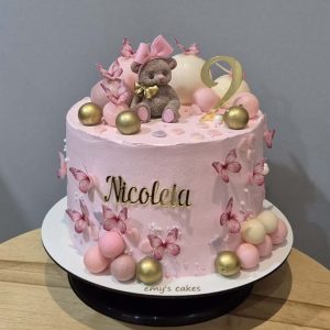 Tort aniversar 2 ani roz Nicola cu ursuleț dormind, fluturași roz, cifra 2, globuri ciocolată roz-aurii, cremă brânză Emys Cakes 3 kg.