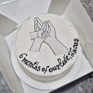 Tort bento cu mâini mici împletite simbol familie, text englezesc „6 months of our life” de la Emys Cakes – comemorare 6 luni bebeluș
