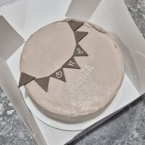 Tort bento pentru 1 lună bebeluș de la Emys Cakes, cu decor minimalist roz pal, steaguri triunghiulare și text „1 MONTH”