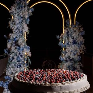 Tort nuntă rotund cu cremă albă și fructe proaspete căpșuni afine, decorat cu flori albastre, 26 kg, Emys Cakes.