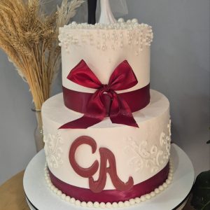 Tort de nuntă alb cu două etaje, figurine miri și fundă burgundy, decor cu perle și inițiale CA, Emys Cakes