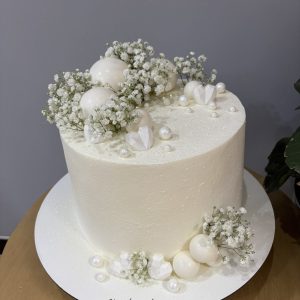 Tort de nuntă alb cu efect de pudră, decorat cu flori gypsophila, perle și globuri elegante, Emys Cakes