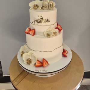 Tort de zi de naștere alb pe două etaje, decorat cu flori din ciocolată, căpșuni și detaliu „50”, Emys Cakes