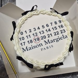 Bento tort alb cu inscripția „Maison Margiela Paris”, decorat cu margine din cremă și fundițe negre, Emys Cakes