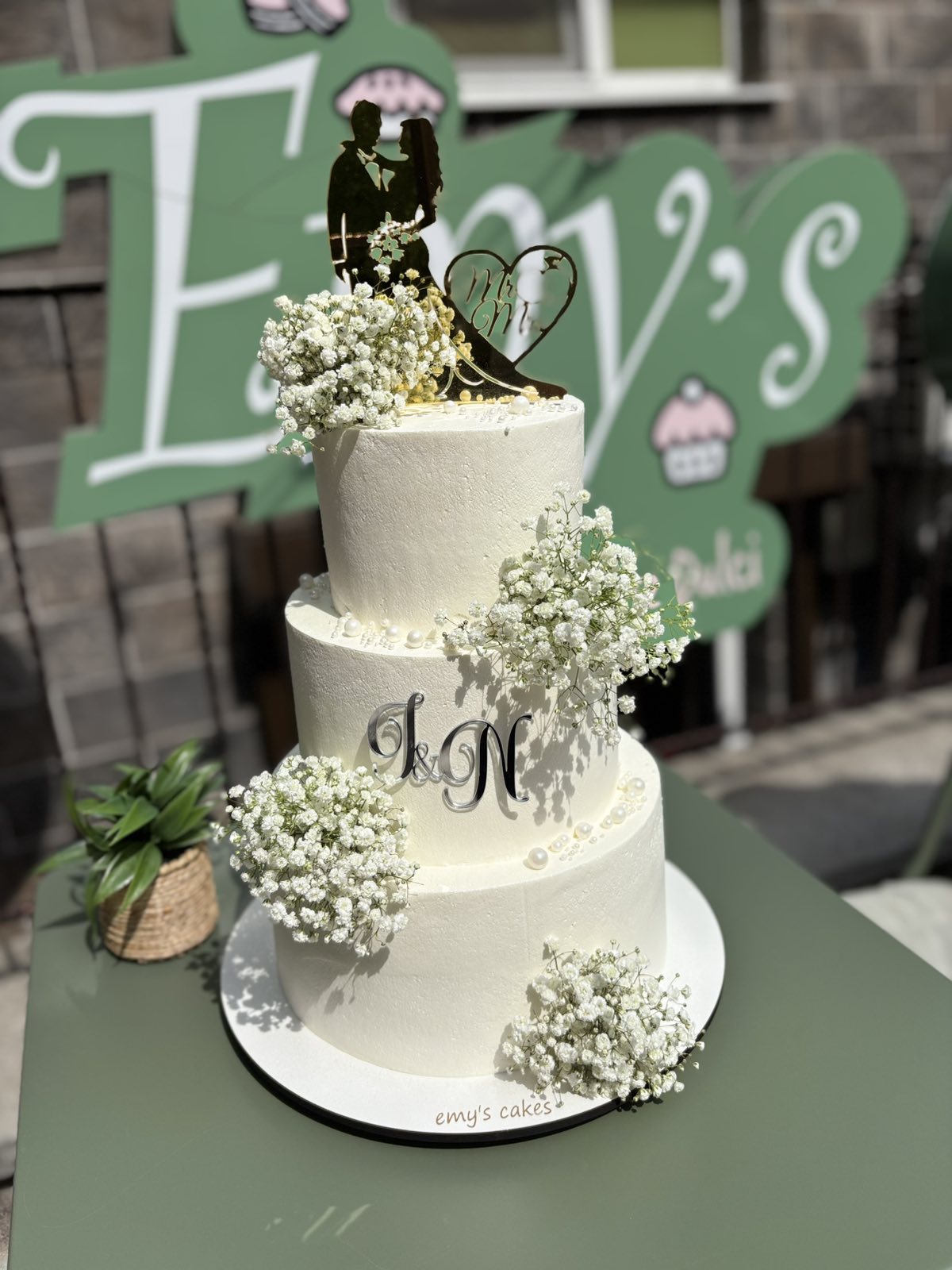Tort de nuntă alb pe trei etaje, acoperit în crem chesse, decorat cu gipsofilă și inițiale metalice, Emys Cakes